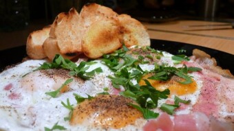 Fried eggs on bacon with garlic bread and black pepper