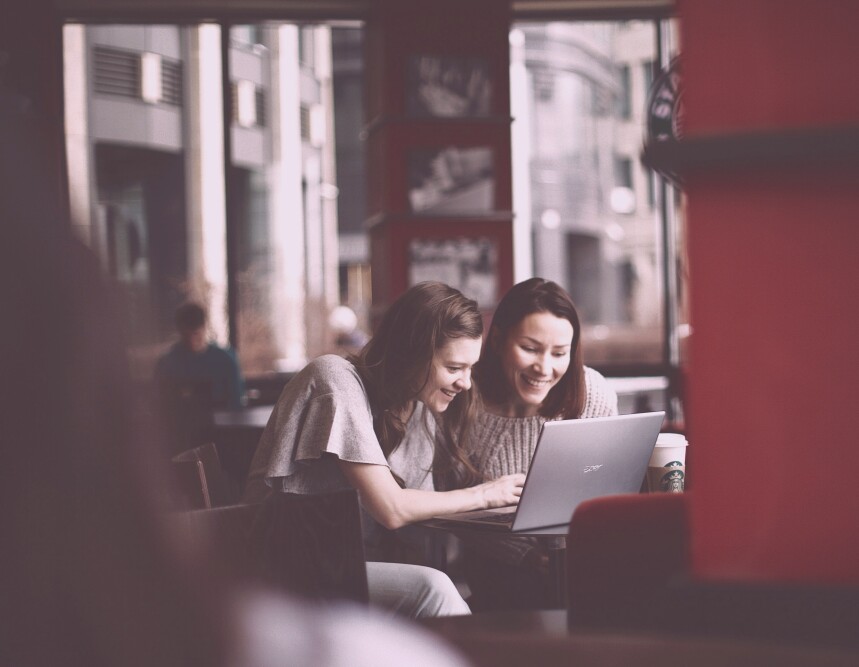 two women at a coffee shop working on their laptop