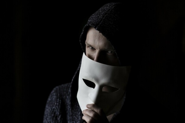 a man hiding half of his face with a white mask