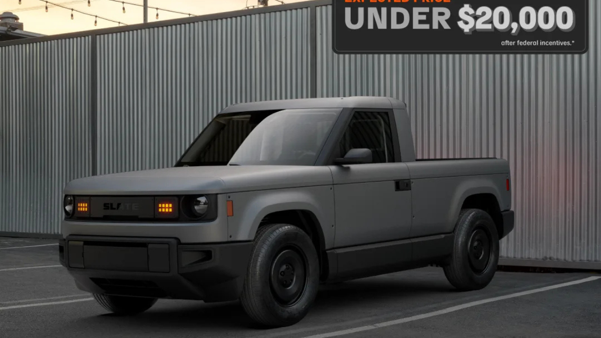 Slate Truck parked in front of a corrugated steel wall, showcasing its minimalist, rugged design with a starting price under $20,000.