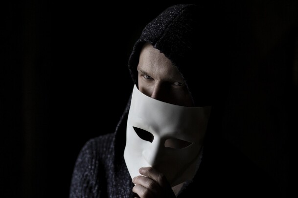a man hiding half of his face with a white mask