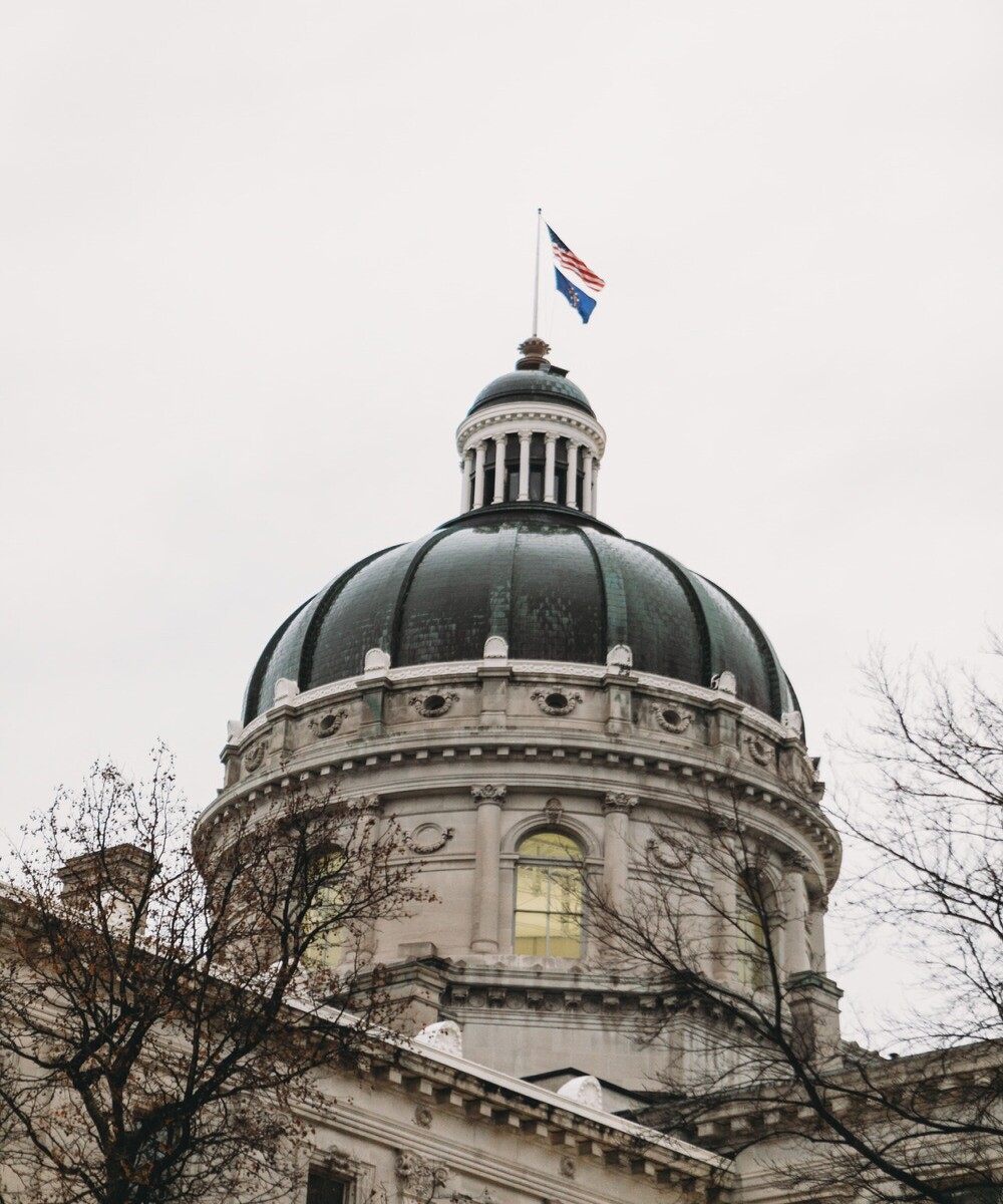 dome of indiana statehouse with american flag and indiana state flag on top