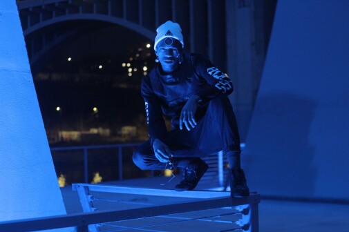 J. Personnage avec lumière bleue sous un pont