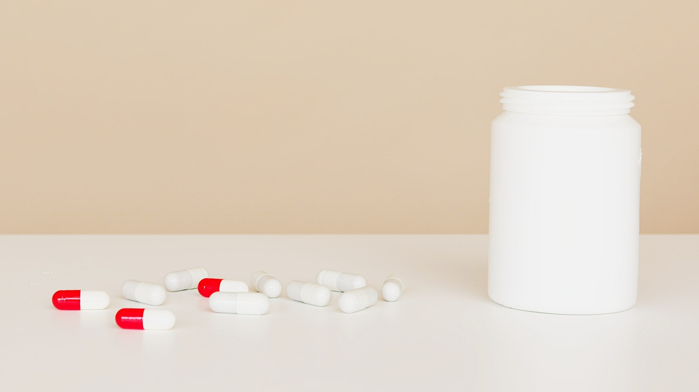Plastic jar with pile of capsules on a table