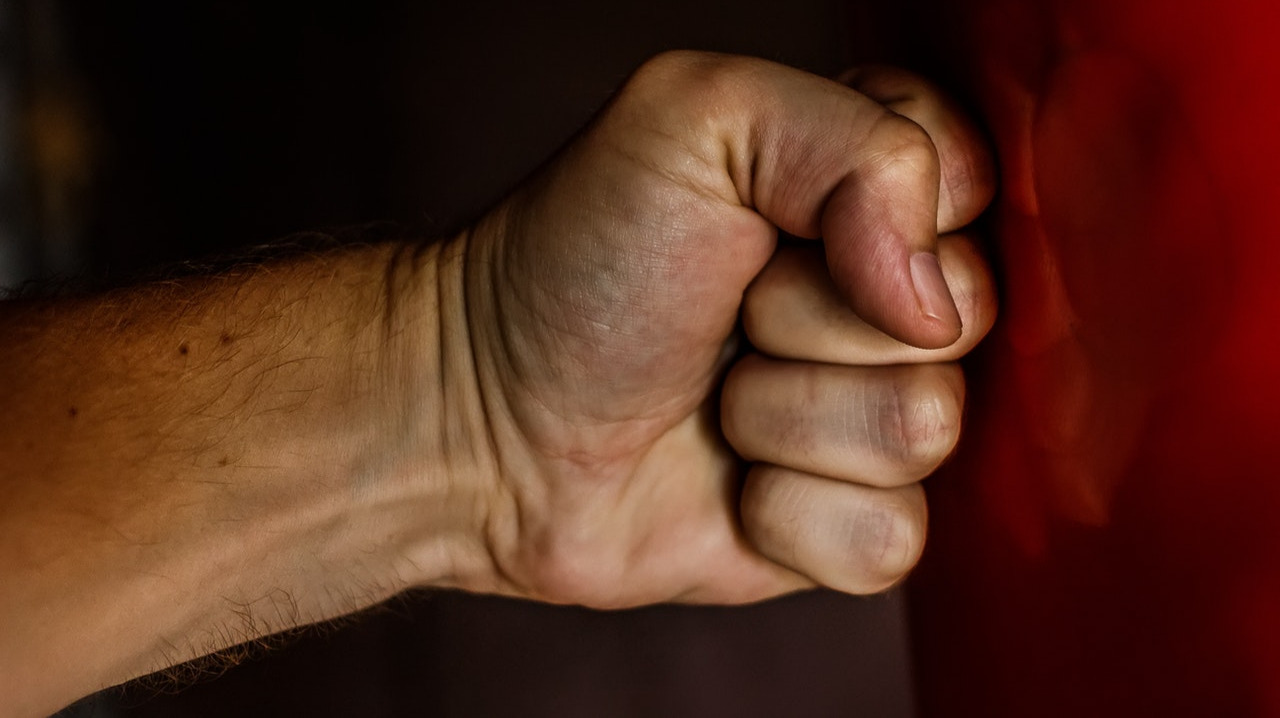 Human fist punching a red wall