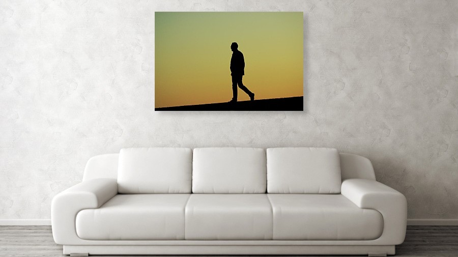 silhouette of a man walking on a low wall at sunset.