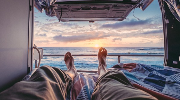 Man reading a book while sitting outside his van