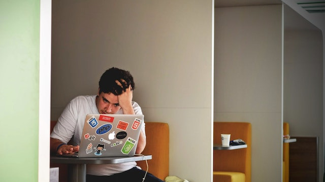 Man in a white shirt using a Macbook Pro