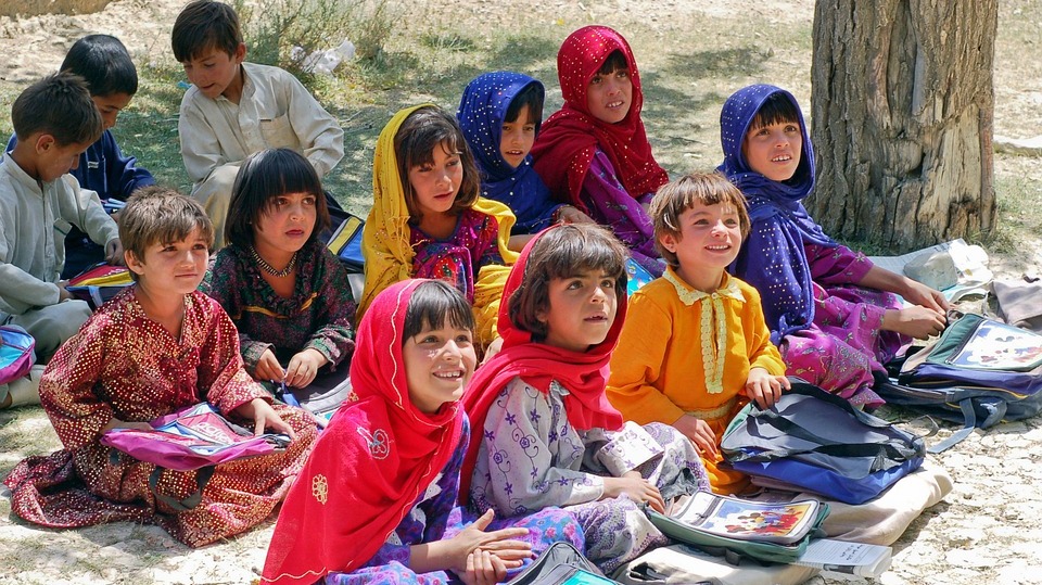Image of Afghan children attending school together outdoors. From Pixabay.