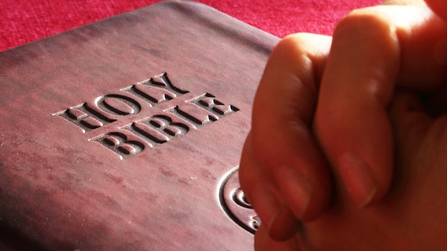 Person's hands on a closed Bible