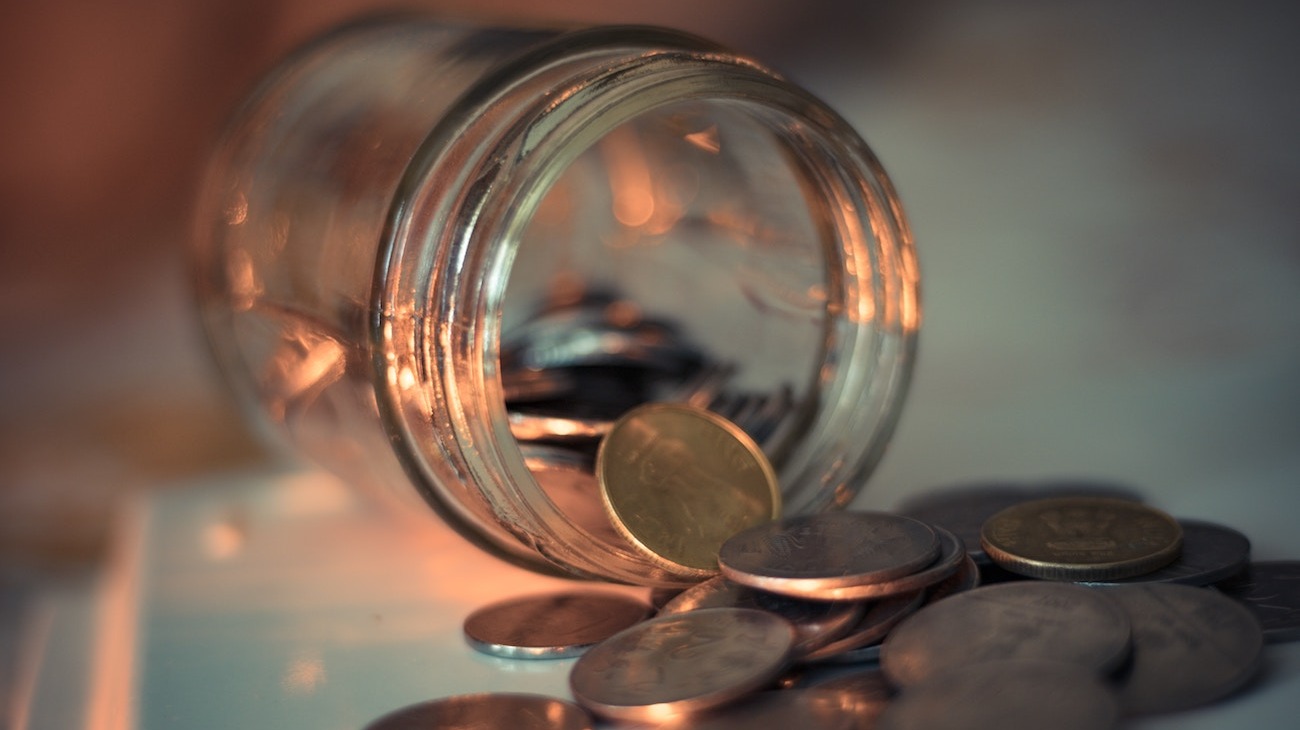 Coins spilling out of a glass jar