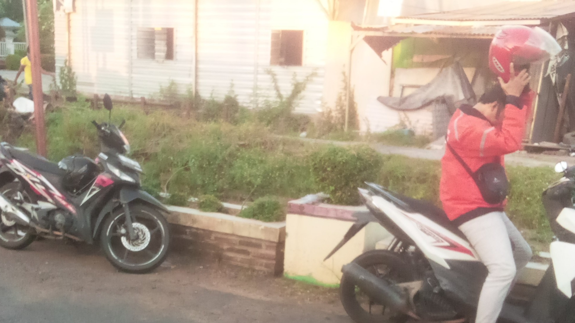 A 45-year-old Indonesian ojol driver preparing for a ride on the street, capturing the reality of a Web3 content creator work