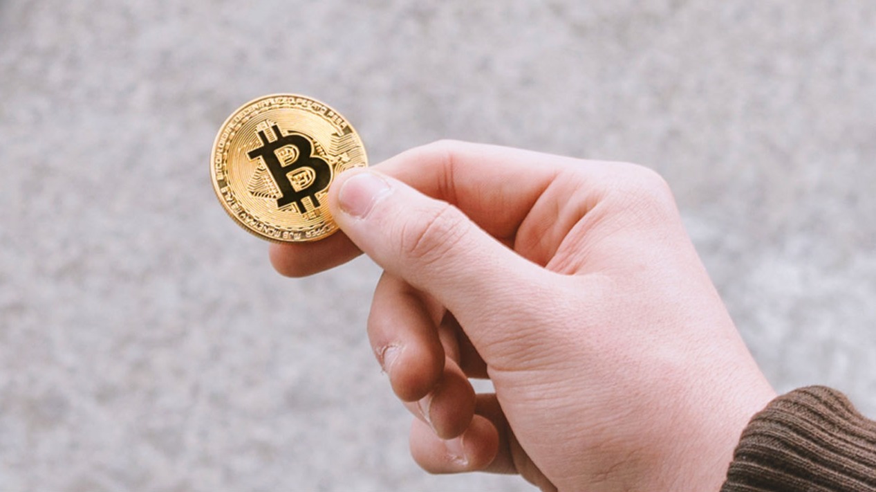 man's hand holding bitcoin