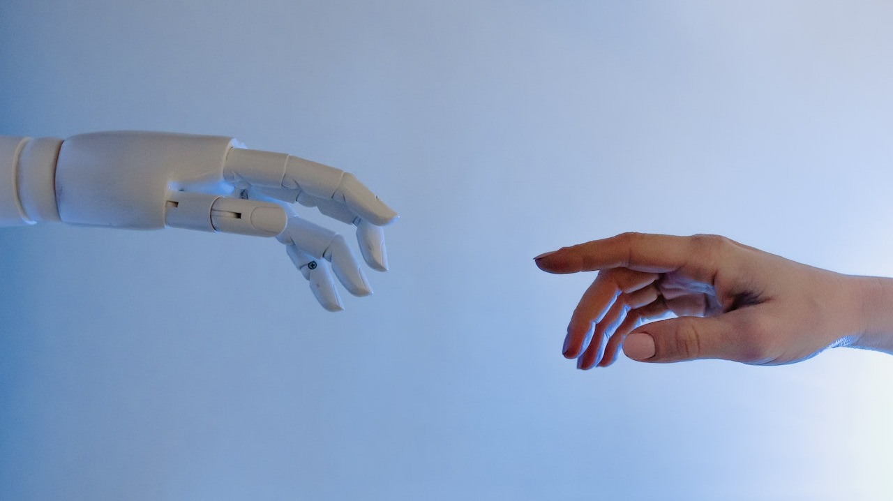 Human hand reaching out to a robotic hand