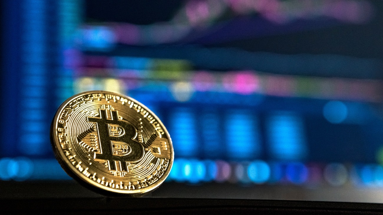 Gold Bitcoin in front of computer display