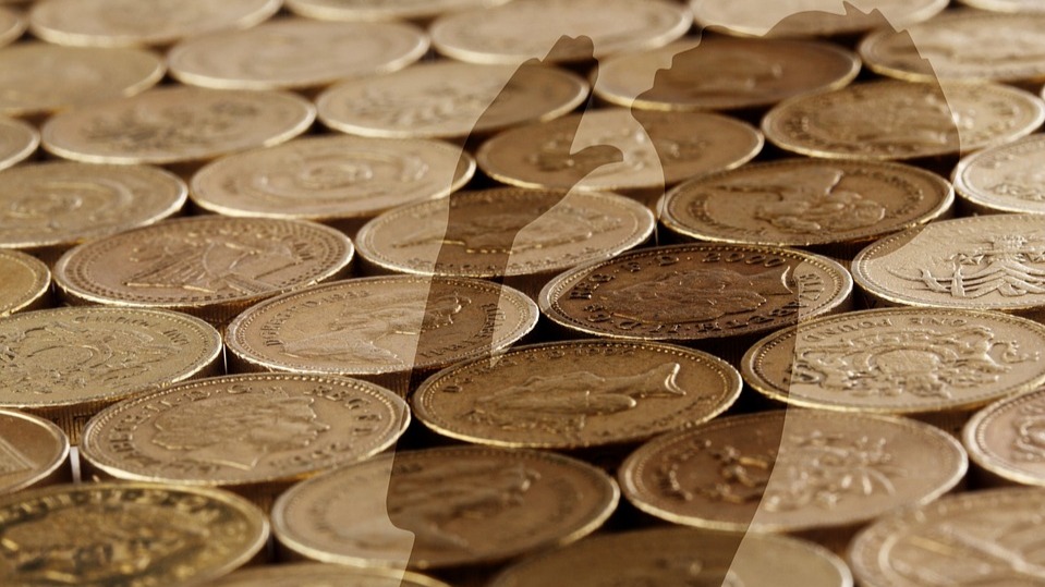 The shadow of a person praying (Christian-style) super-imposed over gold colored coins. From Pixabay.