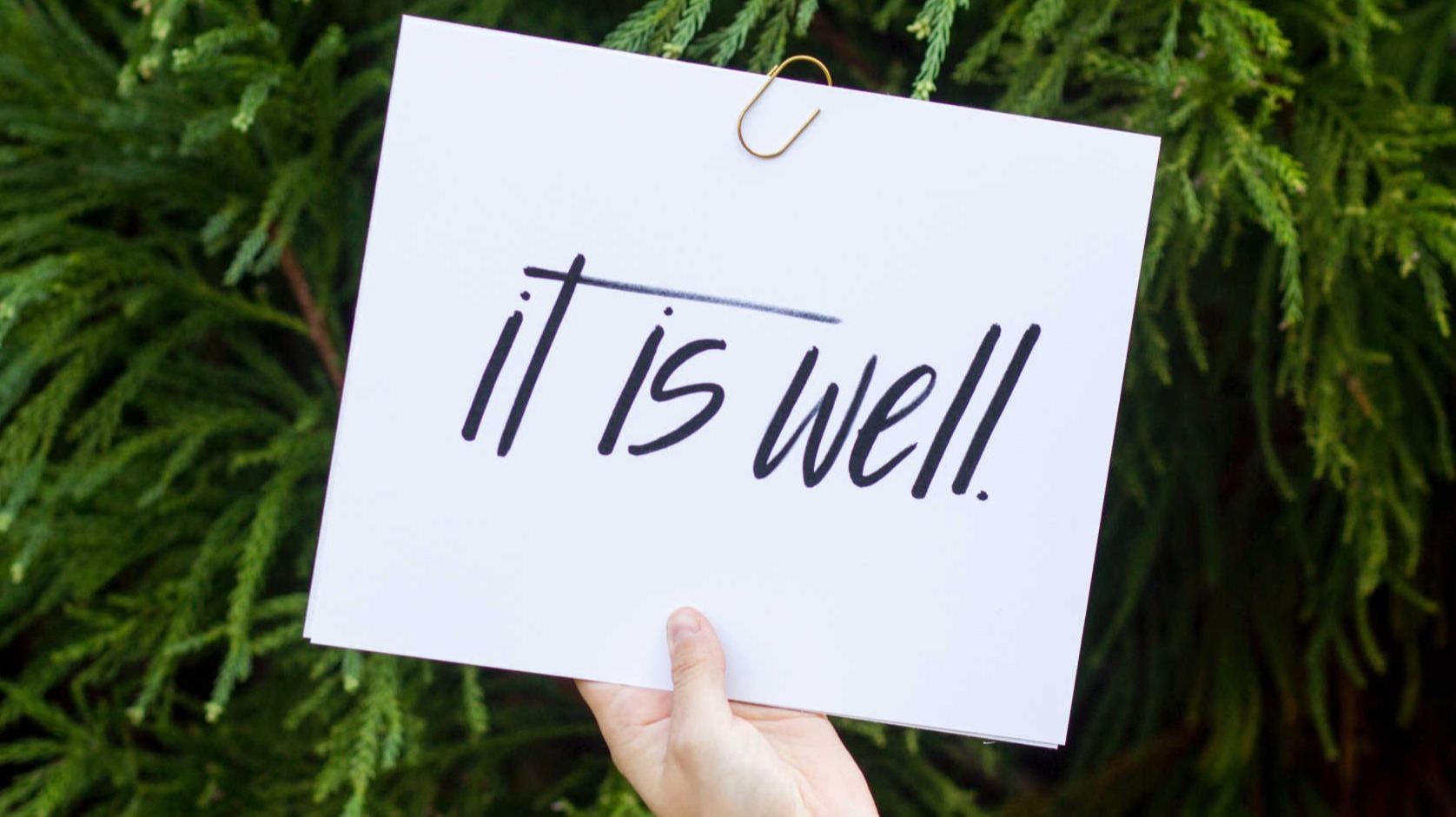 Hand holding sign that say it is well