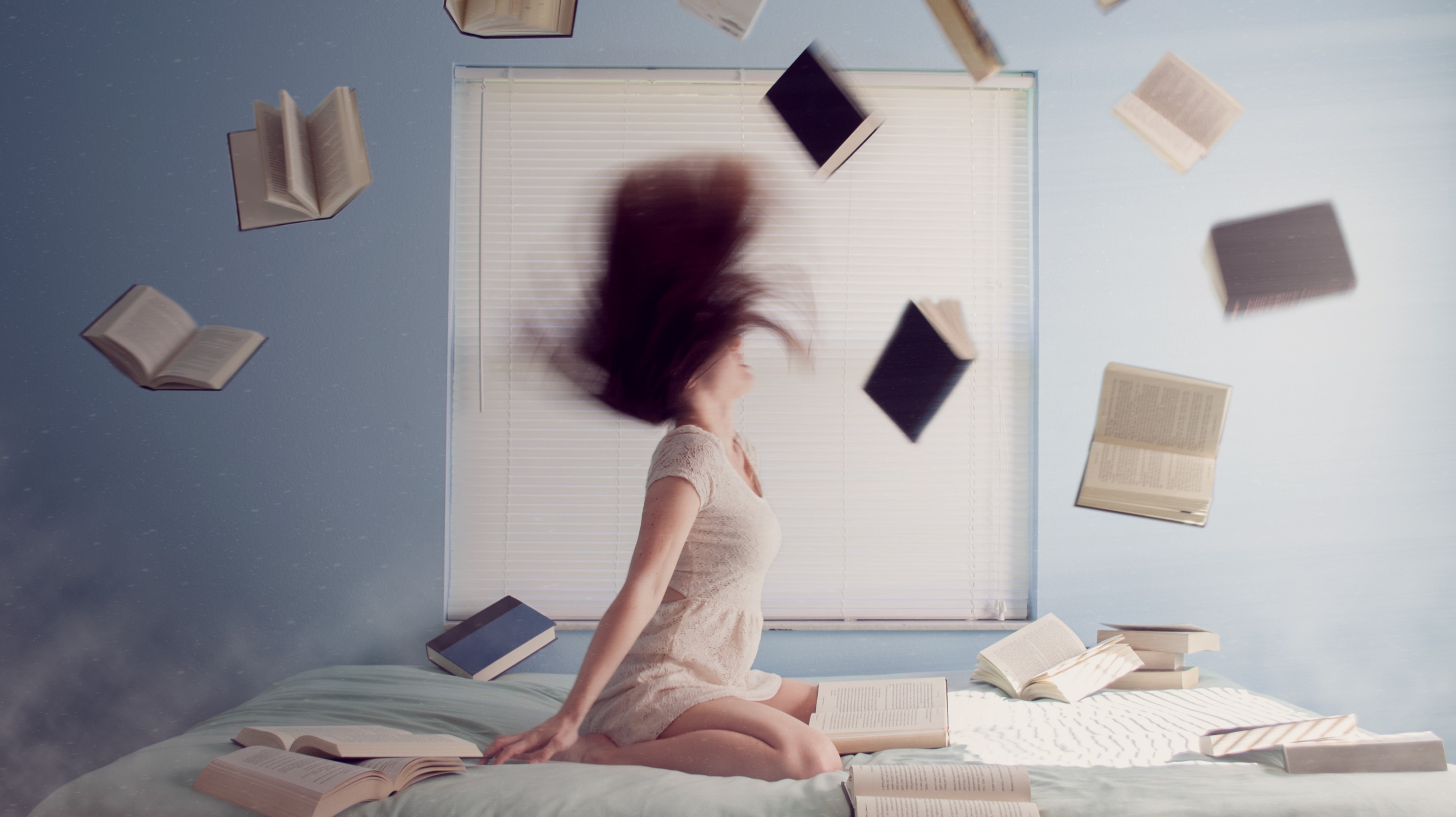 woman on bed with books flying around