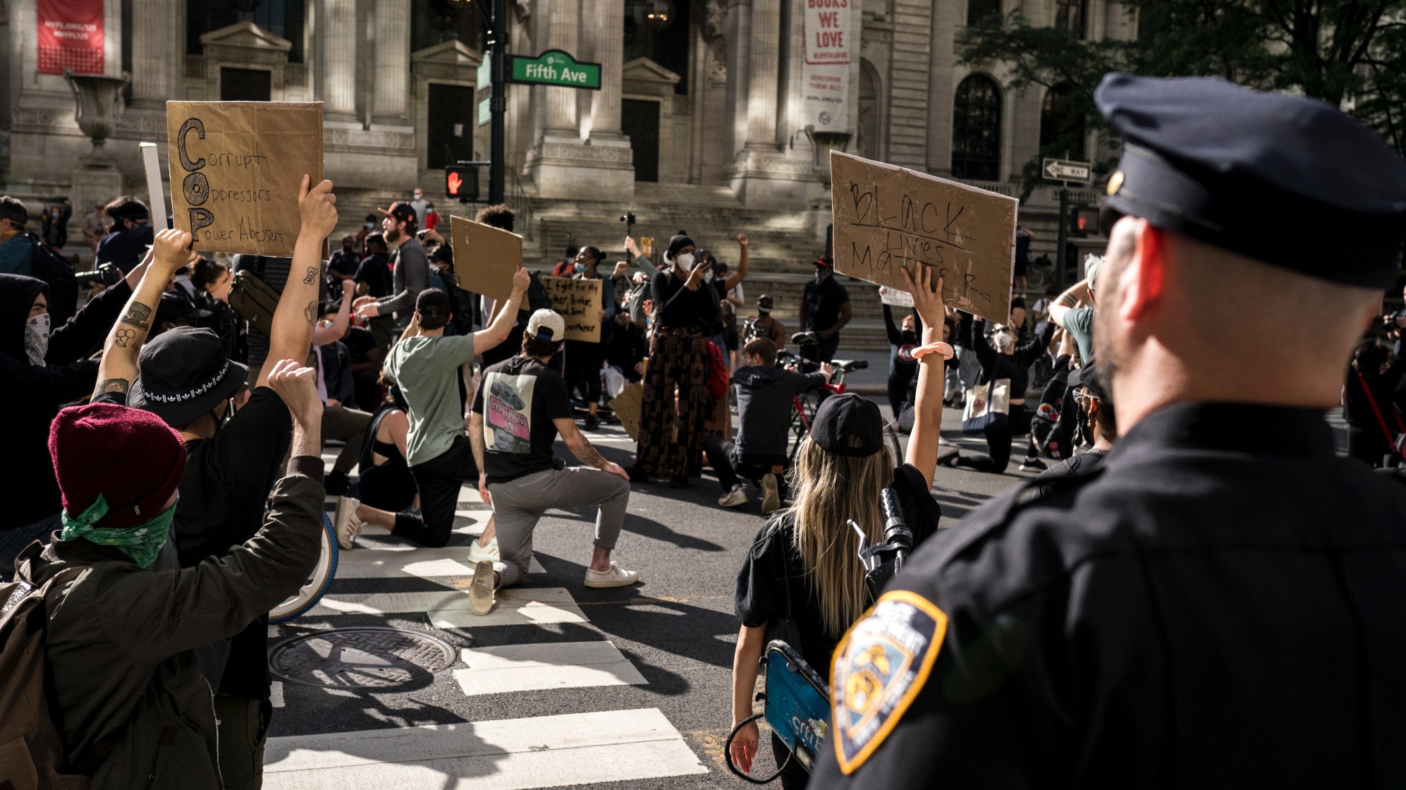 Crowd of protesters holding signs and kneeling
