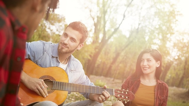 Diverse friends having fun in the sun with a guitar