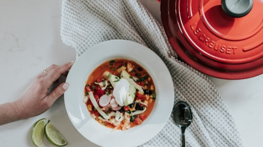 a bowl of soup next to a cast iron pot