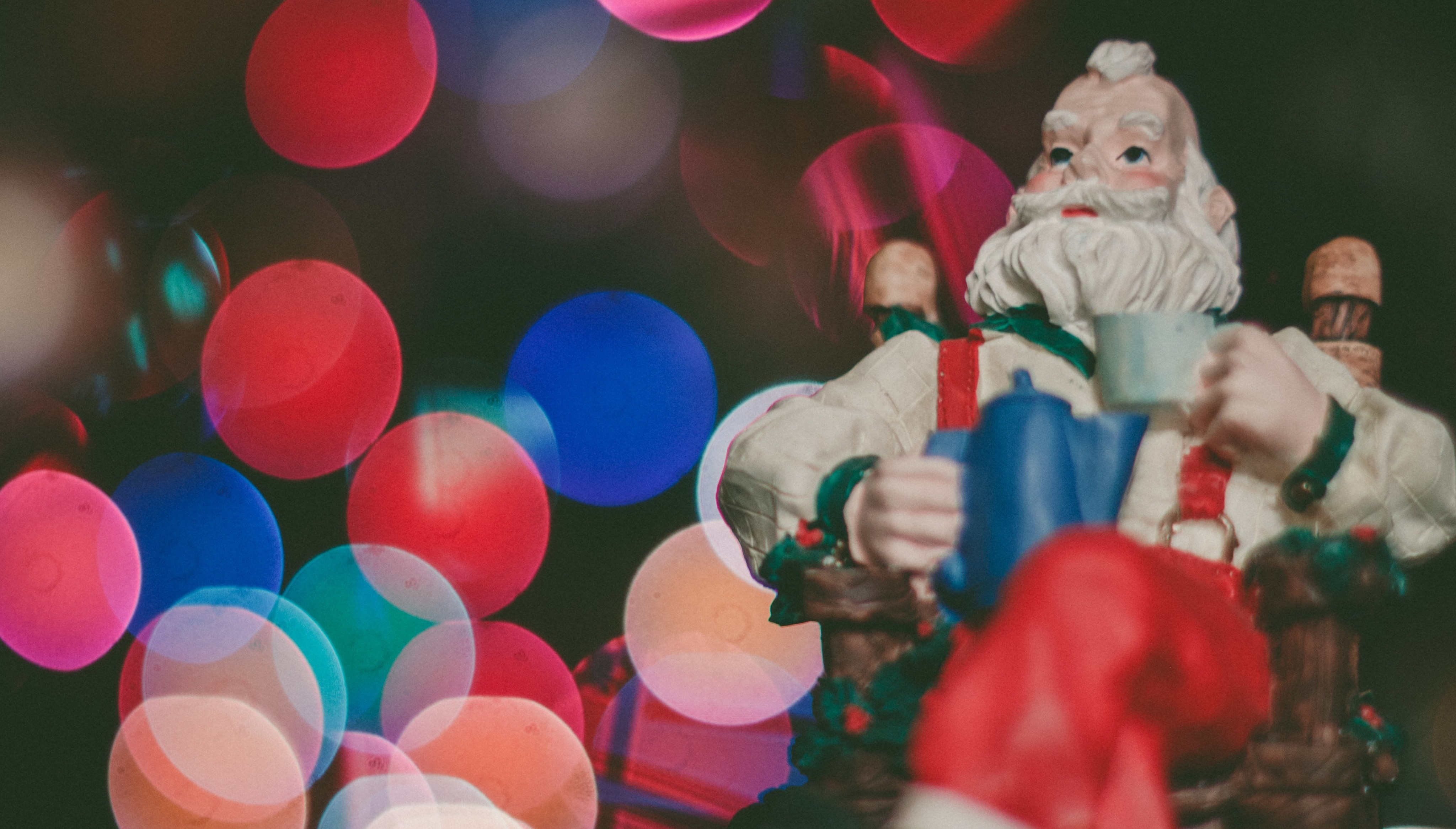 Photo by Caleb Woods on Unsplash, macro photo of santa ornament on lit christmas tree